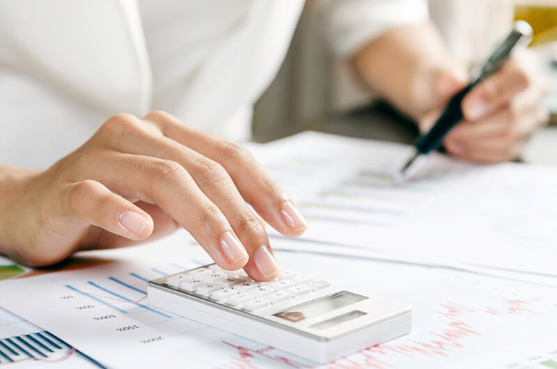 Eine Person benutzt einen Taschenrechner und einen Stift.