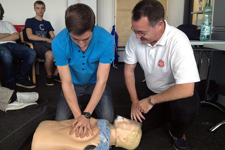 Ein Mann demonstriert CPR an einer Puppe.