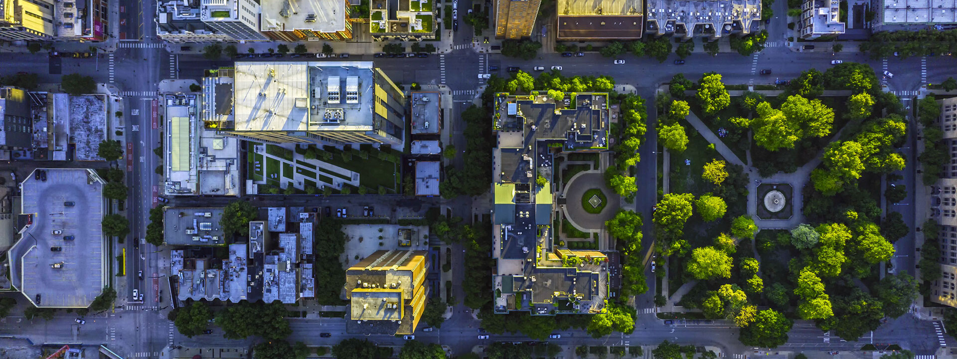 Luftaufnahme einer Stadt mit vielen Gebäuden und Bäumen, im Kontext von Kapsch TrafficComs Bemühungen zur Verbesserung der Luftqualität in urbanen Gebieten.