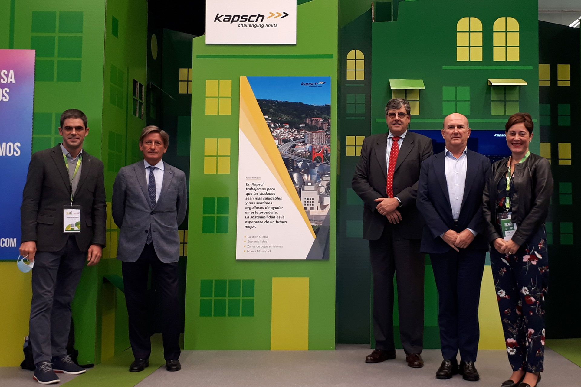 Eine Gruppe von Männern in Anzügen steht vor einer grünen Wand.