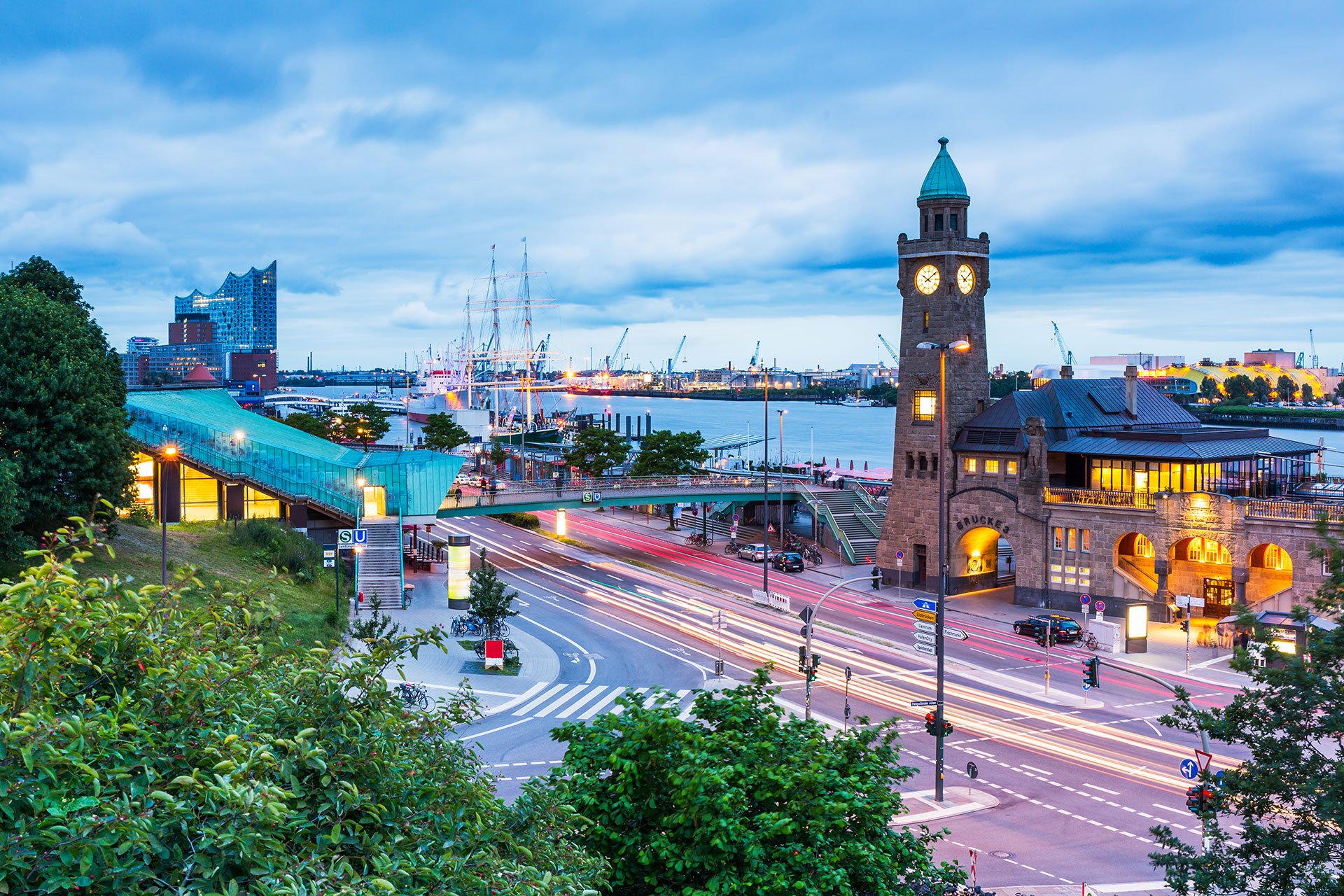 Eine Stadtstraße mit einem Uhrturm und einer Brücke über einem Gewässer.